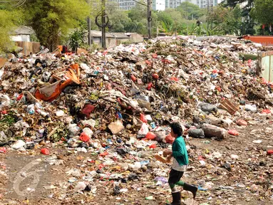 Warga melintas di dekat tumpukan sampah yang ada di Tempat Pembuangan Sampah Sementara Kalibata, Jakarta, Rabu (4/11/2015). Penumpukan sampah terkait aksi pemblokadean jalan menuju TPST Bantar Gebang. (Liputan6.com/Helmi Fithriansyah)