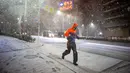 Seorang pria berlari di tengah hujan salju di Koto, Tokyo pada 5 Februari 2024. Situasi ini mendorong badan cuaca Jepang mengeluarkan peringatan salju tebal di seluruh ibu kota. (Philip FONG/AFP)