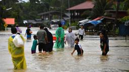 Warga berjalan melewati banjir menyusul hujan lebat di distrik Ran-ngea di provinsi Narathiwat, Thailand selatan (26/2/2022).  Lebih dari 7.200 rumah tangga di 195 desa telah terkena dampak, dengan 6.891 rumah rusak, karena Sungai Sungai Kolok yang diguyur hujan terus meluap. (AFP/Madaree Tohlala)