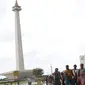 Warga berjalan-jalan di kawasan Monumen Nasional, Jakarta, Jumat (19/4). Libur panjang perayaan Paskah 2019 dimanfaatkan warga untuk berwisata di kawasan Monumen Nasional. (Liputan6.com/Helmi Fithriansyah)