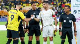 Pemain Al Nassr, Cristiano Ronaldo (kanan) bersalaman dengan pemain Ittihad FC, Karim Benzema sebelum sepak mula pada laga lanjutan Liga Arab Saudi di King Abdullah Sports City, Jeddah, Arab Saudi, Sabtu (07/12/2024) dini hari WIB. (AFP)