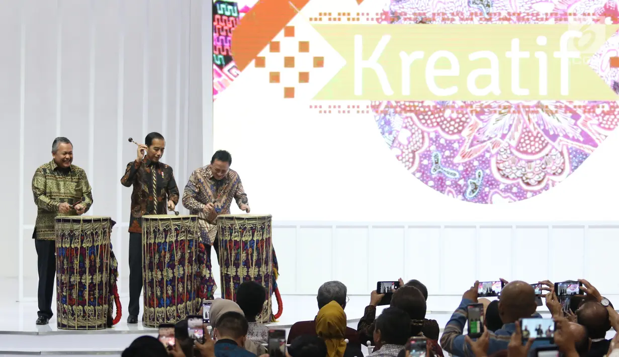 Presiden Joko Widodo (tengah) didampingi Gubernur Bank Indonesia Perry Warjiyo dan Kepala Bekraf Triawan Munaf (kiri) memukul gendang Beleq sebagai tanda peresmian pembukaan pameran Karya Kreatif Indonesia (KKI) 2019 di JCC Senayan, Jumat (12/7/2019). (Liputan6.com/Angga Yuniar)