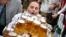 Oliver Struempfel membawa gelas bir sambil berjalan untuk memecahkan rekor pada festival tradisional Gillamoos di Abensberg, Jerman, Minggu (3/9). Ia berhasil menyusun 29 gelas dan membawanya dengan dua tangan dalam sekali jalan (Matthias Balk/dpa via AP)