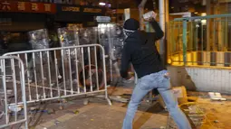 Pengunjuk rasa melemparkan batu ke arah polisi anti huru-hara di Mongkok, Hong Kong, Selasa (9/2). Kerusuhan dimulai ketika pemerintah daerah mencoba untuk menertibkan PKL yang beroperasi. (REUTERS / Bobby Yip)