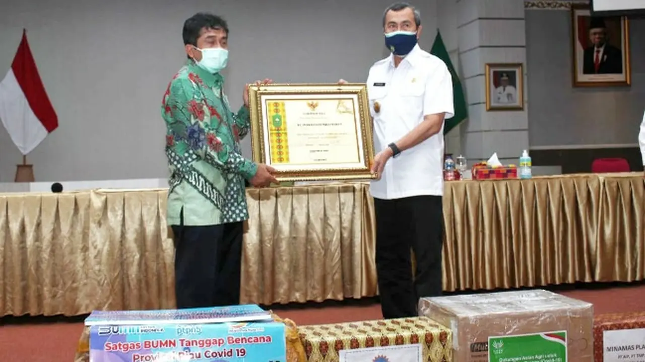 Gubernur Riau Syamsuar menyerahkan penghargaan kepada SEVP Operasional PTPN V Ospin Sembiring karena kepedulian terhadap Covid-19 di Riau.