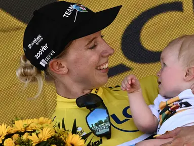 Pebalap Tim DSM, Lorena Wiebes menggendong anaknya saat merayakan kemenagannya di etape pertama Tour de France Wanita 2022 yang menempuh jarak sepanjang 81,6 km dari Tour Eiffel hingga Champs-Elysees, Paris pada 24 Juli 2022. (AFP/Jeff Pachoud)