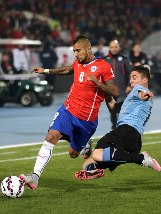 Gelandang Chile, Arturo Vidal (kiri) berusaha melewati gelandang Cristian Rodriguez di perempat final Copa Amerika 2015 di National Stadium, Santiago, Chile, (25/6/2015). Chile melaju ke semifinal usai mengalahkan Uruguay 1-0. (REUTERS/Henry Romero)