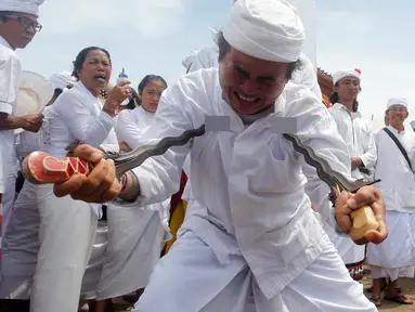 Seorang pria menusukkan keris ke tubuhnya saat menggelar ritual Melasti di Bali, Senin (4/3). Ritual Melasti ini dirayakan menjelang Nyepi 2019. (AP Photo/Firdia Lisnawati)
