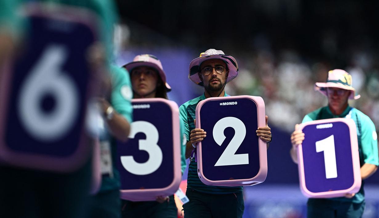 Para volunteer sedang bersiap memasang nomor lintasan untuk nomor lari 800m putra cabang atletik Olimpiade Paris 2024 di Stade de France, Paris, Prancis pada 7 Agustus 2024. (AFP/Jewel Samad)