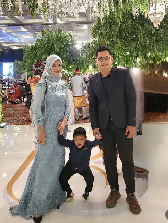 Bersama si kecil dan suami, Lisya tampil mengenakan dress baby blue dengan lengan organzanya saat kondangan. Credit: (@lisyanurrahmii)