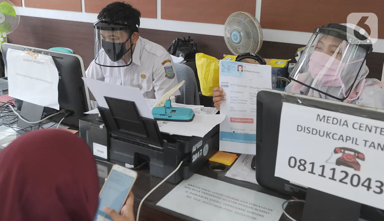 Petugas Dinas Kependudukan dan Catatan Sipil menggunakan pelindung wajah saat melayani warga di Kecamatan Pamulang, Tangerang Selatan, Rabu (3/6/2020). Sejumlah kantor pelayanan pemerintah melaksanakan protokol kesehatan yang ketat untuk memutus rantai penyebaran covid-19. (merdeka.com/Arie Basuki)