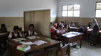 Siswa SDN 4 Kedoyo Tulungagung, Jawa Timur, berbagi ruang belajar dengan papan (Liputan6.com/Zainul Arifin)