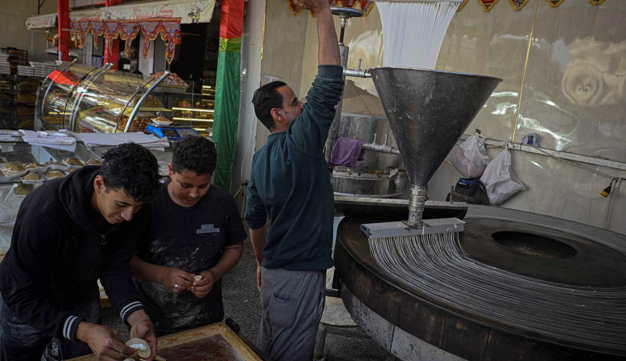 Dengan tekstur yang unik, lembut di dalam dan renyah di luar jika digoreng, kue ini memberikan rasa manis yang khas untuk memulihkan energi setelah berpuasa. Tampak dalam foto, para pembuat roti Mesir menyiapkan kue tradisional Qatayef (kiri) dan Kunafa (kanan), yang dibuat selama bulan suci Ramadan, di tokonya, Kairo, Mesir, pada Kamis 12 Maret 2026. (Khaled DESOUKI/AFP)