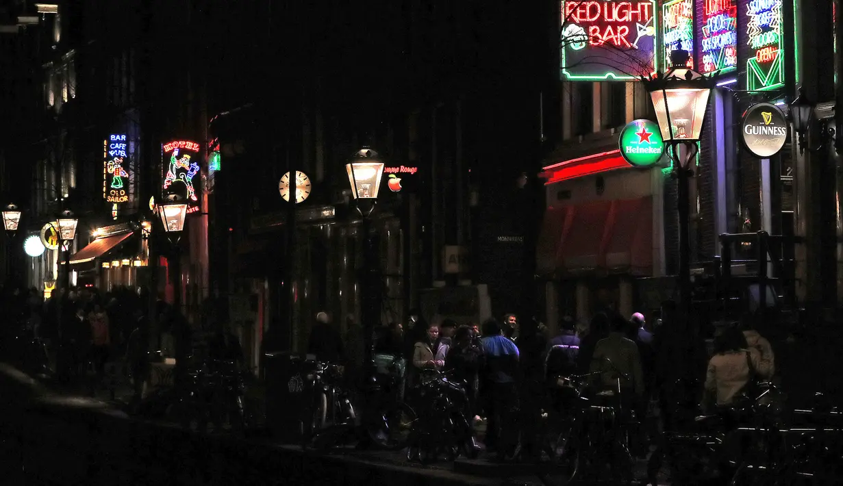Orang-orang berjalan melewati rumah bordil di Red Light District Amsterdam, Belanda, Rabu (3/4). Tidak sedikit dari turis jalan-jalan ke Red Light District karena penasaran. (REUTERS/Yves Herman)