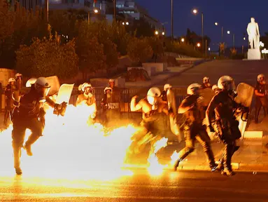 Polisi mencoba menghindari api bom molotov saat unjuk rasa anti-bailot di Athena, Yunani, Rabu (15/7/2015). Demonstran memblokir jalan bentuk penentangan kesepakatan bailout yang diklaim demi menyelamatkan Yunani. (REUTERS/Yannis Behrakis)