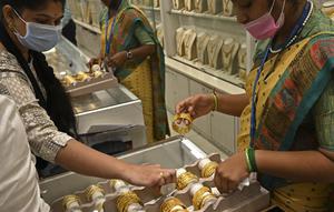 Seorang pelanggan (kiri) memeriksa gelang emas selama festival Hindu 'Akshaya Tritiya', hari keberuntungan dalam kalender Hindu untuk membeli barang-barang berharga, di ruang pamer perhiasan di Chennai, India, Selasa (3/5/2022). Membeli emas adalah kegiatan yang populer di Akshaya Tritiya, karena ini adalah simbol utama kekayaan dan kemakmuran. (Arun SANKAR / AFP)