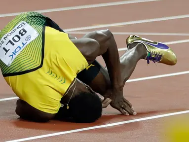 Pelari asal Jamaika, Usain Bolt terkapar di lintasan setelah terjatuh di final 4x100 meter pada Kejuaraan Dunia Atletik di London, Sabtu (12/8). Bolt sempat tertatih-tatih sebelum akhirnya jatuh dan gagal melanjutkan lomba. (AP/Matthias Schrader)