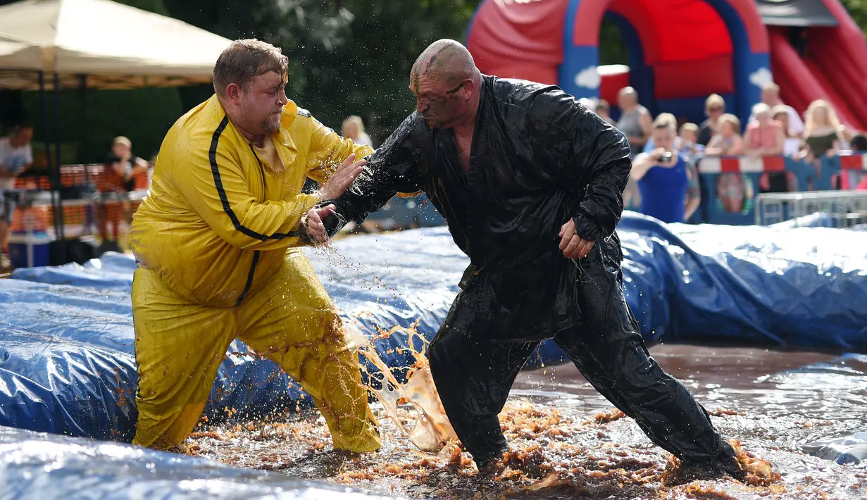 Dua orang pegulat beraksi saat mengikuti World Gravy Wrestling Championships ke-10 di Rose 'n' Bowl Pub di Inggris (28/8). Dalam pertandingan gulat ini, peserta mengenakan pakain unik saat bertanding. (AFP Photo/Oli Scarff)