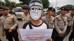 Massa menggunakan topeng saat menggelar aksi unjuk rasa di depan Istana Merdeka, Jakarta, Selasa (7/4/2015). Mereka menagih janji Presiden Jokowi mencabut moratorium terkait larangan pengiriman TKI ke Timur Tengah. (Liputan6.com/Faizal Fanani)