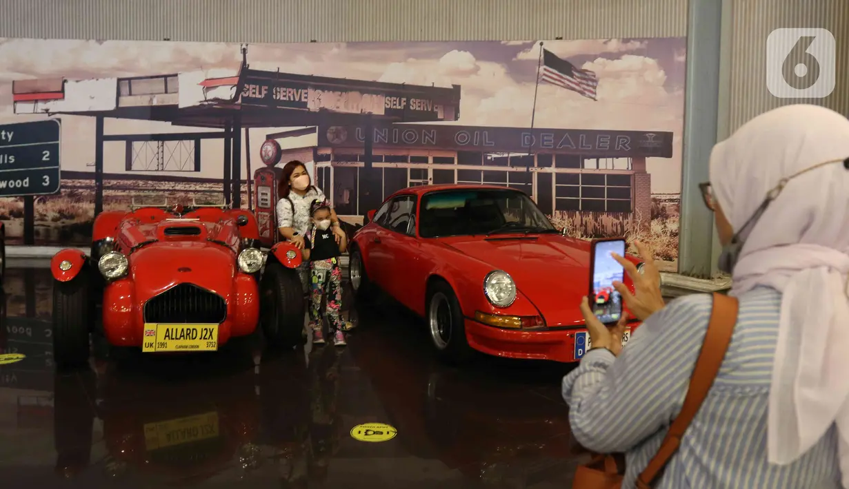 Pengunjung berfoto dengan mobil antik di Museum Angkut, Kota Batu, Jawa Timur, Kamis (15/12/2022). Museum Angkut merupakan museum transportasi dan tempat wisata modern. (Liputan6.com/Herman Zakharia)