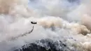 Sebuah helikopter militer menjatuhkan air di atas hutan dekat Desa Schinos, Korintus, Yunani, Kamis (20/5/2021). Kebakaran hutan besar di sebelah barat Athena merusak rumah-rumah dan mendorong evakuasi. (AP Photo/Petros Giannakouris)