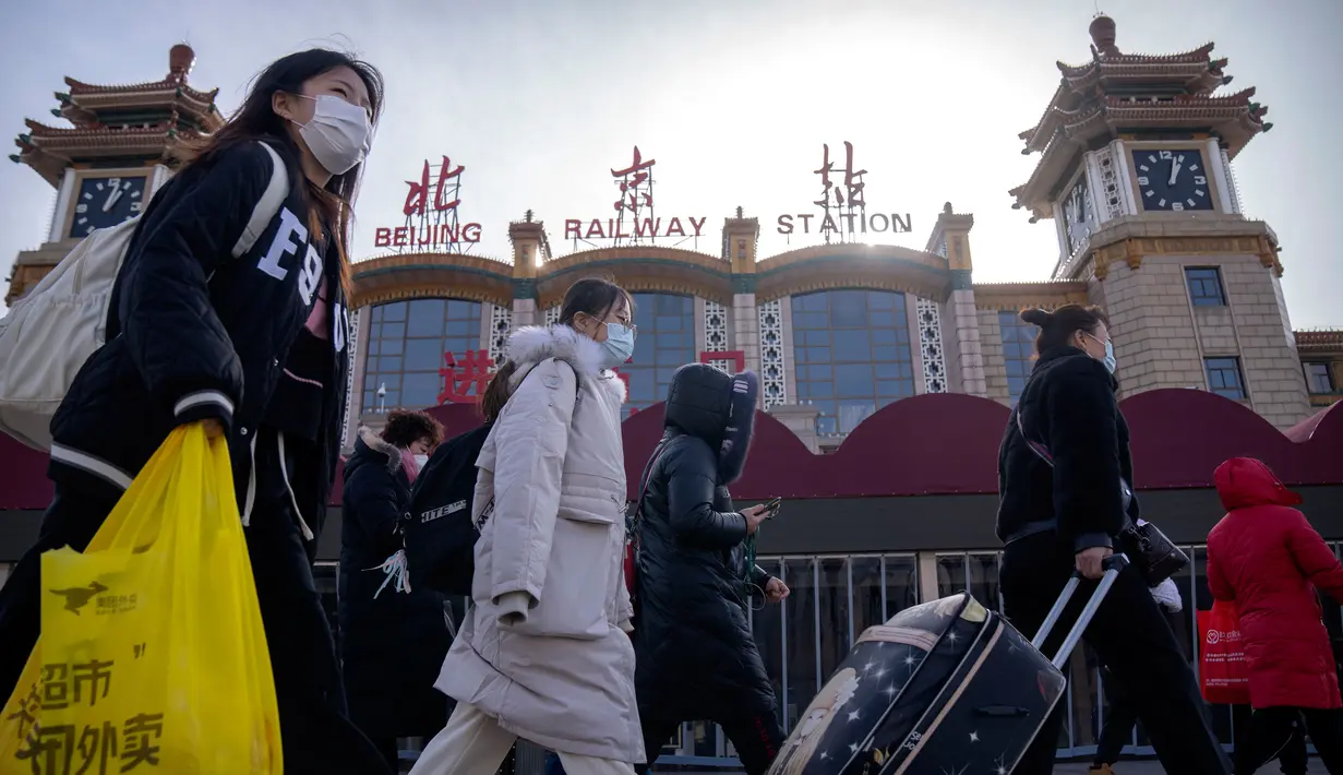 Para pemudik yang memakai masker berjalan melewati pintu masuk Stasiun Kereta Api Beijing di Beijing, China, Sabtu (14/1/2023). Jutaan warga China diperkirakan akan melakukan perjalanan selama periode liburan Tahun Baru Imlek tahun ini. (AP Photo/Mark Schiefelbein)