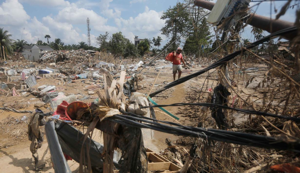 Banjir bandang yang menerjang Kabupaten Aceh Tamiang pada Rabu 26 November 2025, menimbulkan kerusakan parah. Tampak dalam foto, seorang korban membawa tas berisi barang-barang yang diselamatkan di daerah yang terdampak banjir bandang di Aceh Tamiang, Jumat 5 Desember 2025. (AP Photo/Binsar Bakkara)