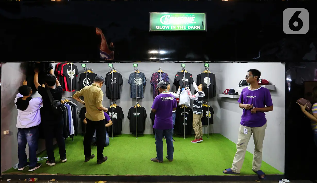 Pengunjung melihat kaus pada JakCloth Year End Sale 2019 di Plaza Tenggara GBK Senayan, Jakarta, Kamis (26/12/2019). Acara yang digelar pada 25-29 Desember 2019 menghadirkan 400 clothing line lokal dan brand internasional. (Liputan6.com/Fery Pradolo)