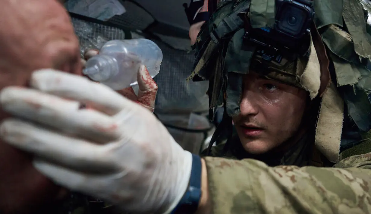 Seorang petugas medis militer memberikan pertolongan pertama kepada seorang tentara yang terluka dalam pertempuran dekat Kremenna di wilayah Luhansk, Ukraina, 16 Januari 2023. Hingga saat ini pejabat Ukraina menolak untuk mengonfirmasi jumlah korban dalam perangnya dengan Rusia, setelah ketua Komisi Uni Eropa pada akhir November 2022 lalu memperkirakan bahwa "lebih dari 20.000 warga sipil dan 100.000 tentara Ukraina telah tewas di Ukraina hingga saat ini." (AP Photo/LIBKOS)