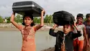 Dua anak etnis Rohingya dari Myanmar berjalan membawa barang-barang mereka di atas kepala menuju Shah Porir Deep, di Teknak, Bangladesh, 31 Agustus 2017. (AP Photo/Suvra Kanti Das)