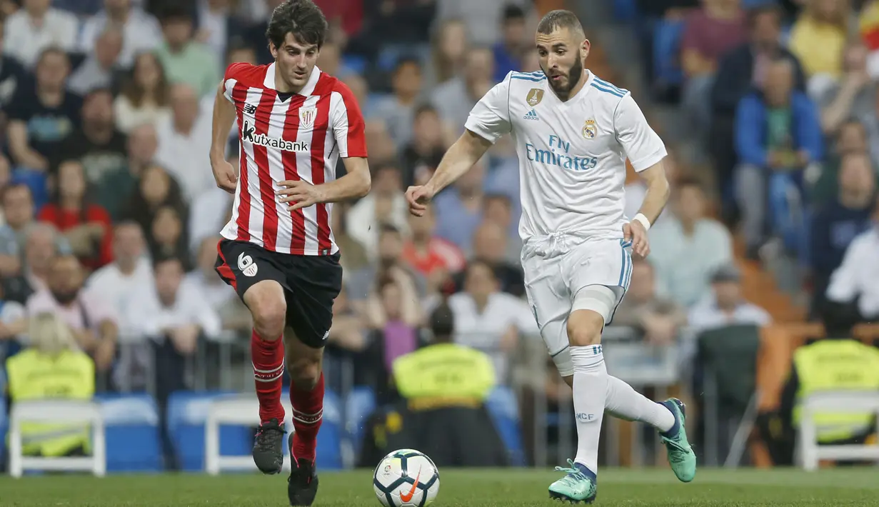 Pemain Real Madrid, Karim Benzema (kanan) berusaha melewati adangan pemain Athletic Bilbao, Mikel San Jose pada lanjutan La Liga Santander di Santiago Bernabeu stadium, Madrid, (18/4/2018). Real Madrid bermain imbang 1-1 dengan Bilbao. (AP/Francisco Seco)