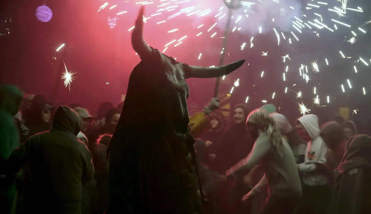 Seorang warga berpakaian seperti hantu dengan memegang tongkat kembang api selama perayaan " Correfocs ", Mallorca, Spanyol, (24/1). Orang - orang menari sambil men yalakan kembang api diantara kerumunan. (REUTERS / Enrique Calvo)