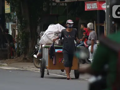 Pemulung melintas di Jalan Raden Saleh, Jakarta, Kamis (30/4/2020). Setiap Ramadan tiba, kemunculan pemulung yang membawa gerobak marak terjadi. Saat ini, kemunculan mereka menjadi masalah tersendiri di tengah upaya memutus mata rantai penyebaran Covid-19. (Liputan6.com/Helmi Fithriansyah)