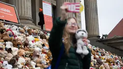 Seorang siswa berswafoto sebelum meletakkan boneka beruang atau Teddy Bears di tangga Concert Hall, Berlin, Kamis (15/3). 740 boneka itu dipajang di tengah kegiatan Organisasi Visi Dunia yang memiliki tujuan misi kemanusiaan. (AFP PHOTO/Odd ANDERSEN)