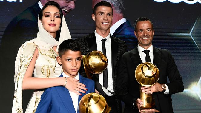 Georgina Rodriguez foto bersama kekasihnya Cristiano Ronaldo, putranya Cristiano Jr dan agen, Jorge Mendes diatas panggung selama Dubai Globe Soccer Awards ke-10 di Dubai (3/1). (AFP Photo/Fabio Ferrari)