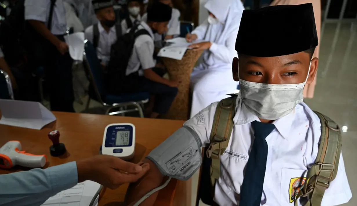 Seorang siswa sekolah menengah pertama menjalani pemeriksaan tekanan darah sebelum menerima dosis vaksin Sinovac pada acara vaksinasi virus corona COVID-19 di Blang Bintang, Provinsi Aceh, 21 September 2021. (CHAIDEER MAHYUDDIN/AFP)