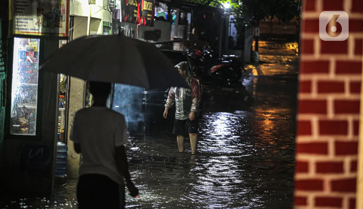 Warga melintasi genangan banjir di kawasan Kemang, Jakarta, Selasa (4/10/2022). Jalan Kemang Utara IX tak bisa dilalui oleh kendaraan. Banjir menggenangi kawasan Pasar Kambing dan sejumlah rumah penduduk. (Liputan6.com/Faizal Fanani)