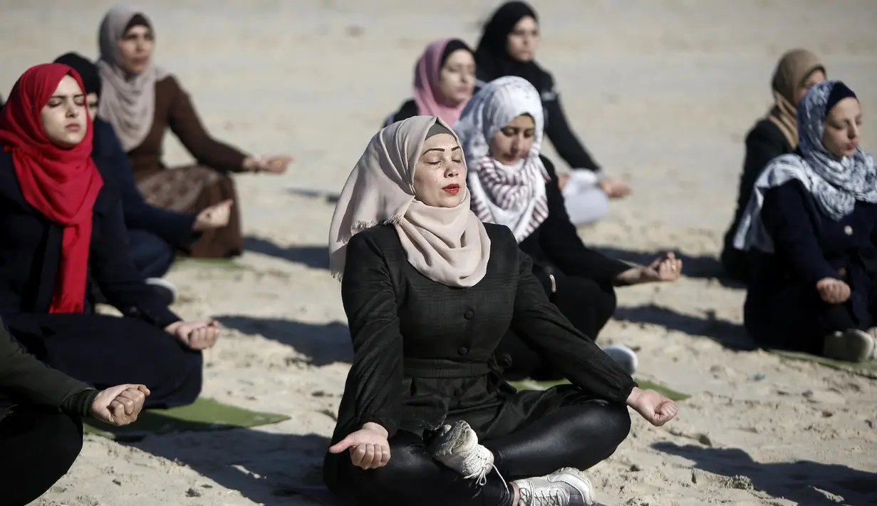 Sejumlah wanita Palestina berlatih yoga di pantai di Gaza City (3/3/2020). Pelatihan yoga tersebut diselenggarakan oleh Positive Energy Club. (AFP Photo/Mohammed Abed)
