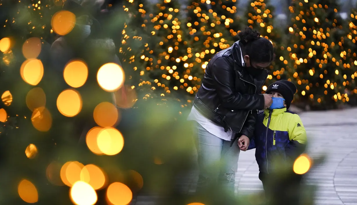 Seorang wanita membantu sang anak membetulkan posisi maskernya di New York, Amerika Serikat (AS) (22/12/2020). Seiring pandemi COVID-19 terus merajalela di seluruh AS tahun ini, masyarakat terpaksa menjalani musim liburan Natal yang lain dari biasanya. (Xinhua/Wang Ying)