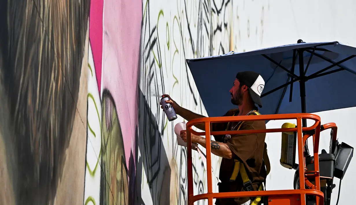 <p>Seniman Argentina, Maximiliano Bagnasco sedang mengerjakan mural besar bergambar Lionel Messi di Wynwood, Miami, 10 Juli 2023. La Pulga akan melakukan debutnya di Inter Miami pada 21 Juli di Piala Liga. (AFP/Chandan Khanna)</p>