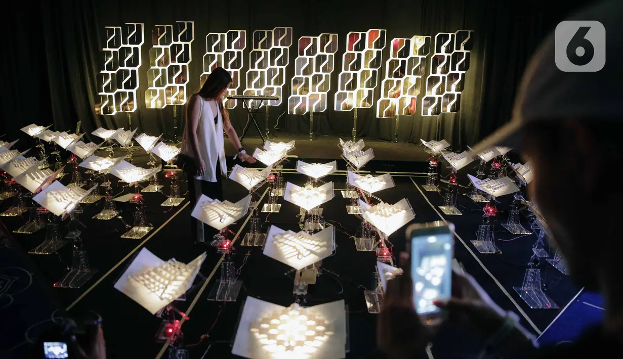 Pengunjung berpose saat mengunjungi pameran seni berbasis teknologi berwujud sorotan cahaya futuristik 'Wave of Tomorrow' di Jakarta, Sabtu (21/12/2019). Pameran seni Wave of Tomorrow menghadirkan 14 karya seni media baru dari 13 kreator Tanah Air dan internasional.  (Liputan6.com/Faizal Fanani)