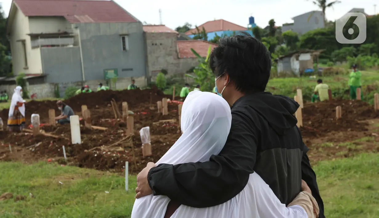 Kerabat menyaksikan pemakaman anggota keluarganya yang dimakamkan dengan protokol COVID-19 di area khusus TPU Srengseng Sawah, Jakarta, Kamis (14/1/2021). TPU Srengseng Sawah mulai menerima pemakaman jenazah dengan protokol COVID-19 sejak Selasa (12/1) lalu. (Liputan6.com/Helmi Fithriansyah)