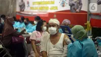 Petugas kesehatan menyuntikkan vaksin booster kepada warga di halaman Masjid Istiqlal, Jakarta, Selasa (5/4/2022). Pemerintah memberlakukan vaksinasi booster sebagai syarat mudik Lebaran tahun ini. (merdeka.com/Imam Buhori)
