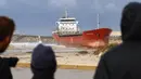 Warga menyaksikan kapal kargo pembawa semen Zelek Star yang terdampar di pantai Laut Mediterania, Kota Ashdod, Israel, Jumat (27/12/20190). Angin kencang dan ombak besar membuat kapal menjauh dari titik jangkar di dekat Pelabuhan Ashdod sehari sebelumnya. (JACK GUEZ/AFP)