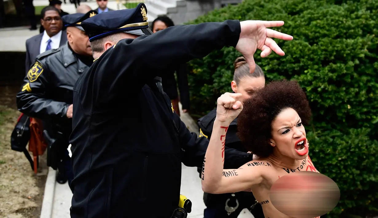 Polisi berusaha menahan pengunjuk rasa wanita yang tampil topless di sidang kekerasan seksual komedian Bill Cosby di Gedung Pengadilan Montgomery, Pennsylvania, Amerika Serikat, Senin (9/4). Wanita terus memaki Bill Cosby. (AP Photo/Corey Perrine)