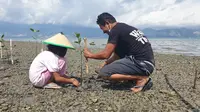 Seorang warga bersama putrinya menanam mangrove di pesisir Kelurahan Panau, Kota Palu, Sabtu (10/4/2021). Aksi tersebut selain sebagai upaya mitigasi dari bencana juga diharapkan meningkatkan hasil tangkap nelayan setempat. (Foto: Dokumentasi KIARA).