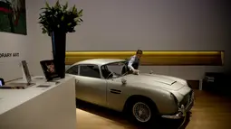 Seorang staf berpose dengan Aston Martin DB5 yang digunakan dalam film James Bond GoldenEye tahun 1995 rumah lelang Bonham, London, Selasa (19/6). Diproduksi mulai 1963 sampai 1965, Aston Martin DB5 bukanlah mobil biasa. (AP/Matt Dunham)