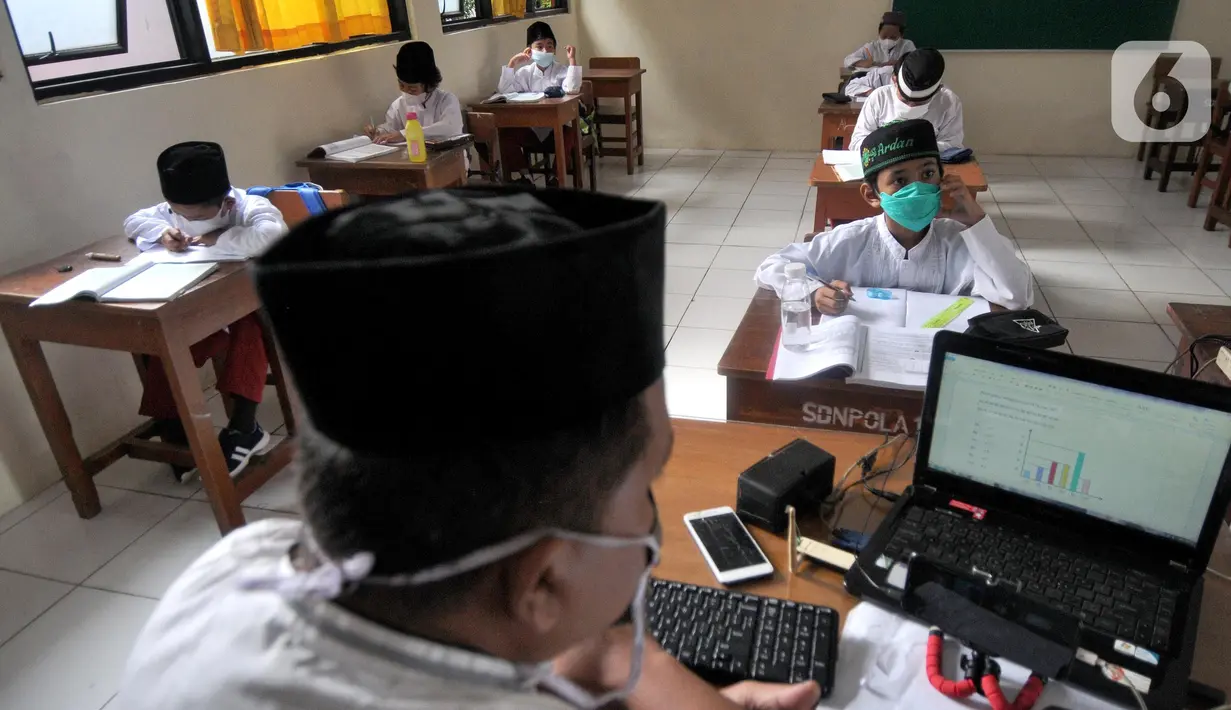 Guru saat mengajar di SDN Pondok Labu 14 Pagi di Cilandak, Jakarta Selatan, Jumat (4/6/2021). Kegiatan belajar tatap muka masih masih menerapkan pola 50 persen siswa belajar di rumah secara online untuk setiap kelas mengantisipasi penyebaran virus covid-19. (merdeka.com/Arie Basuki)