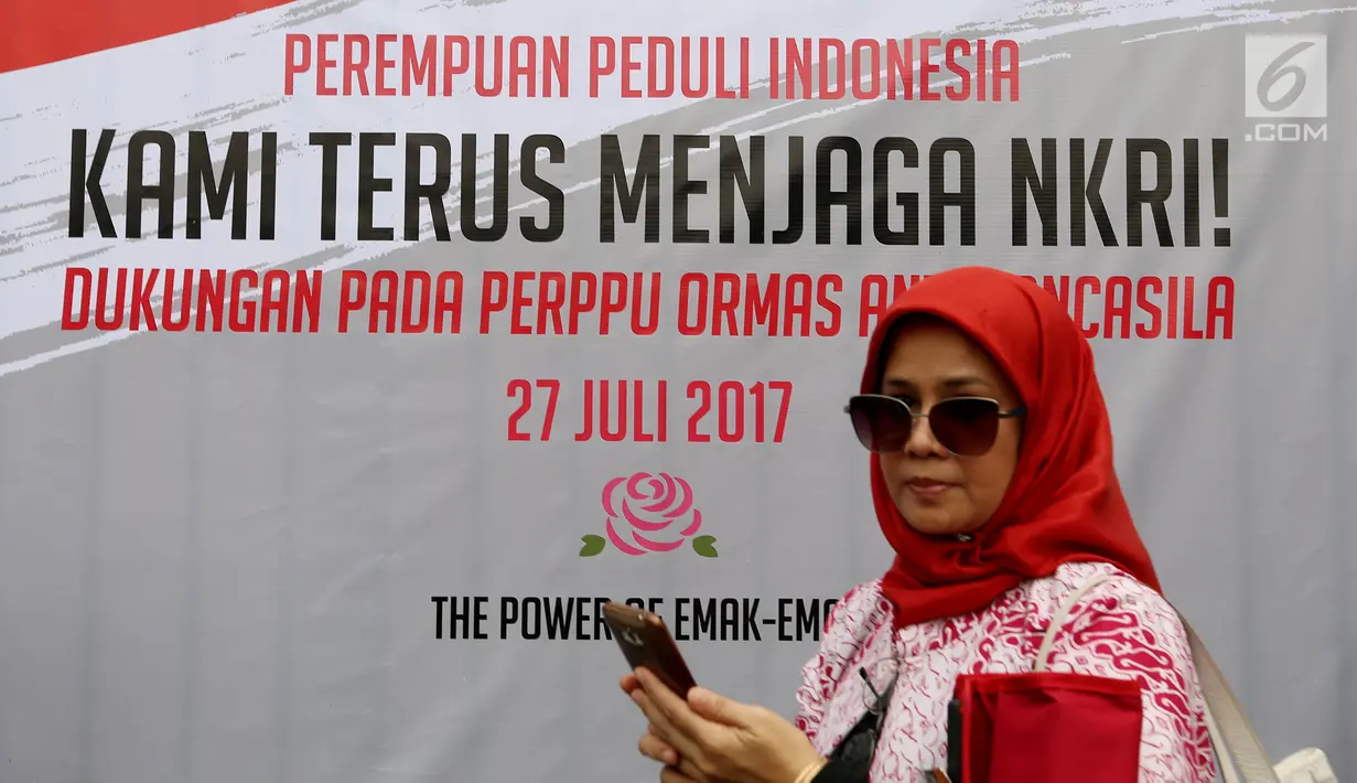 Massa dari Perempuan Peduli Indonesia melintas di depan spanduk mendukung pengesahan Perppu Ormas di depan Gedung DPR RI, Jakarta, Kamis (27/7). Kumpulan para ibu mendesak pemerintah untuk merealisasikan Perppu No 2 Tahun 2017. (Liputan6.com/Johan Tallo)