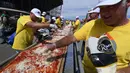 Peserta menaburi keju saat membuat pizza panjang di jalur Auto Club Speedway, di Fontana, California (10/6). Peserta ini membuat pizza untuk memecahkan rekor pizza tepanjang di dunia dengan panjang 1,32 mil atau 2,13 km. (AFP/Mark Ralston)